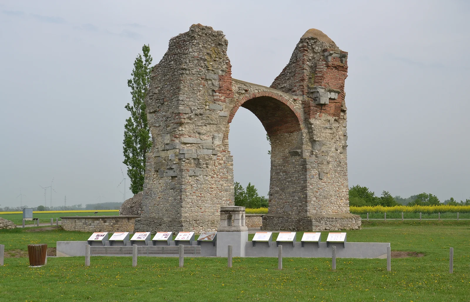 Ancient Roman monumental stone archway standing in a grassy field in Lower Austria.