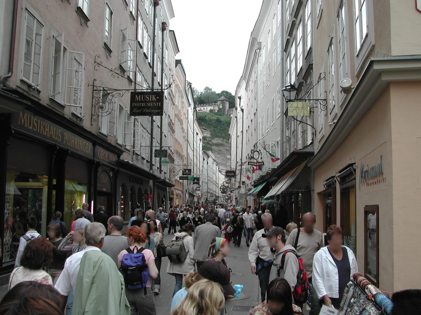Pedestrian shopping street in Salzburg lined with ornate historic metal guild signs.