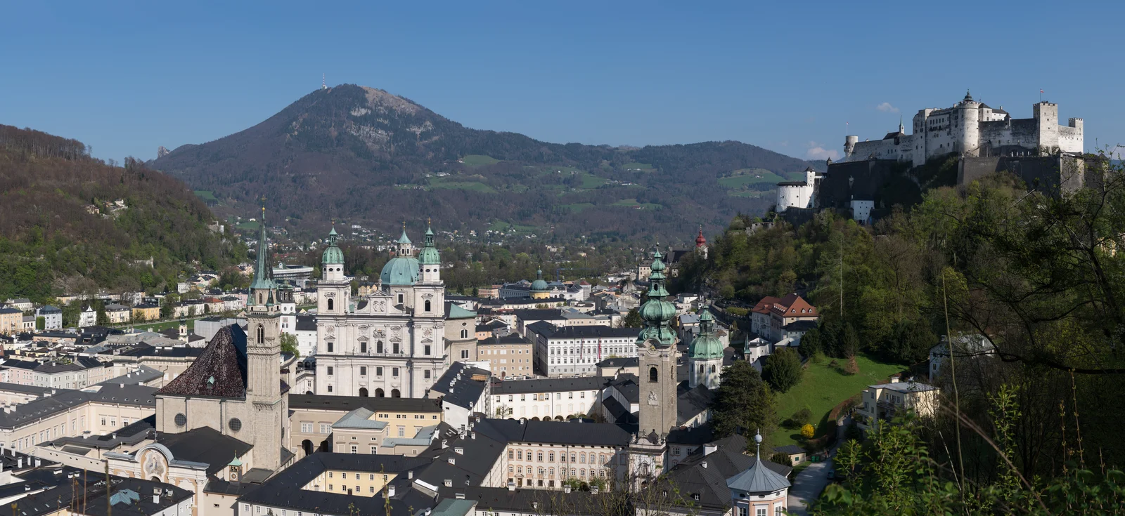 Panoramic view of Salzburg historic old town, baroque church towers, and alpine backdrop.