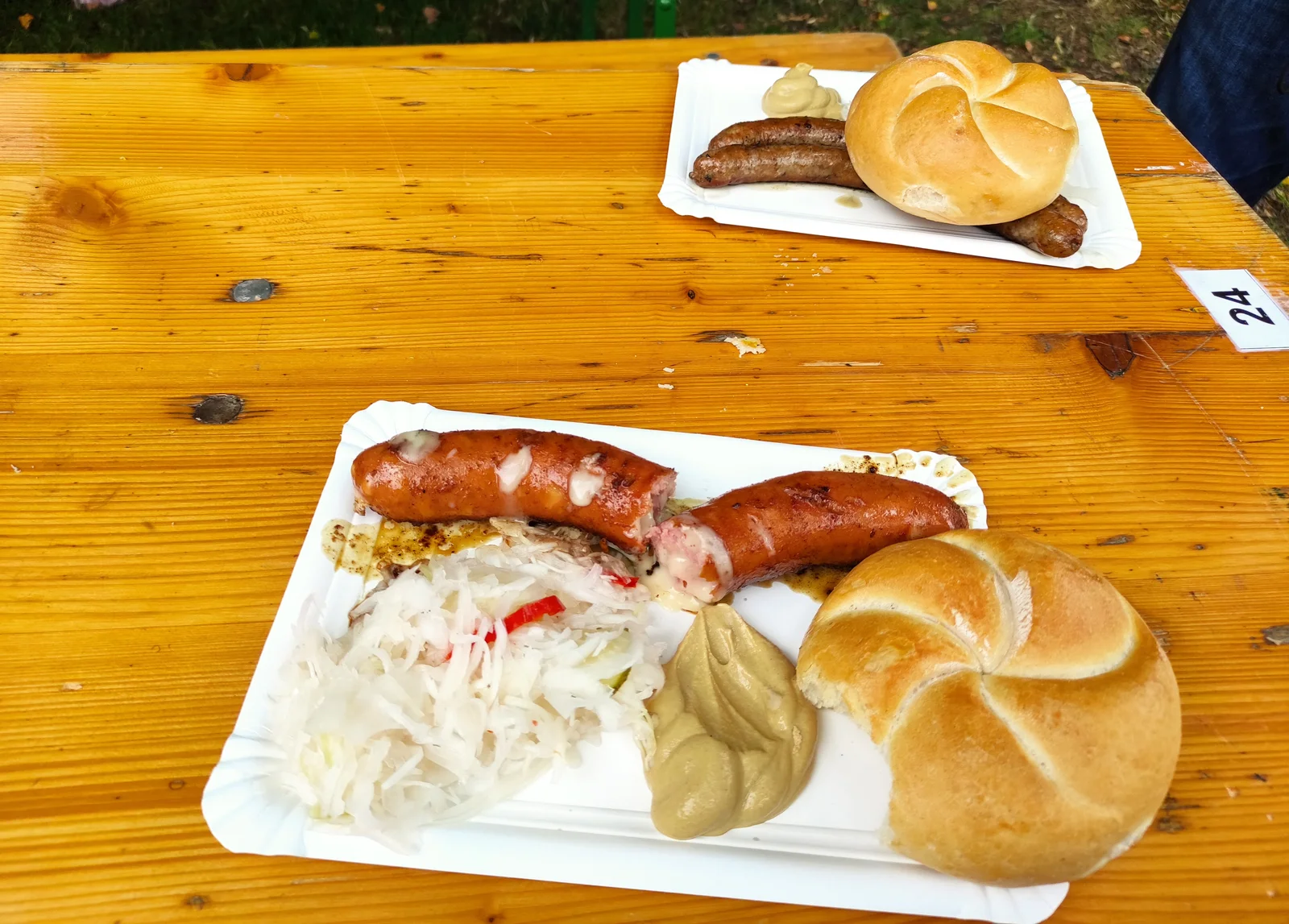 Austrian sausages browning on a flat-top grill with melted cheese crusting on the surface.