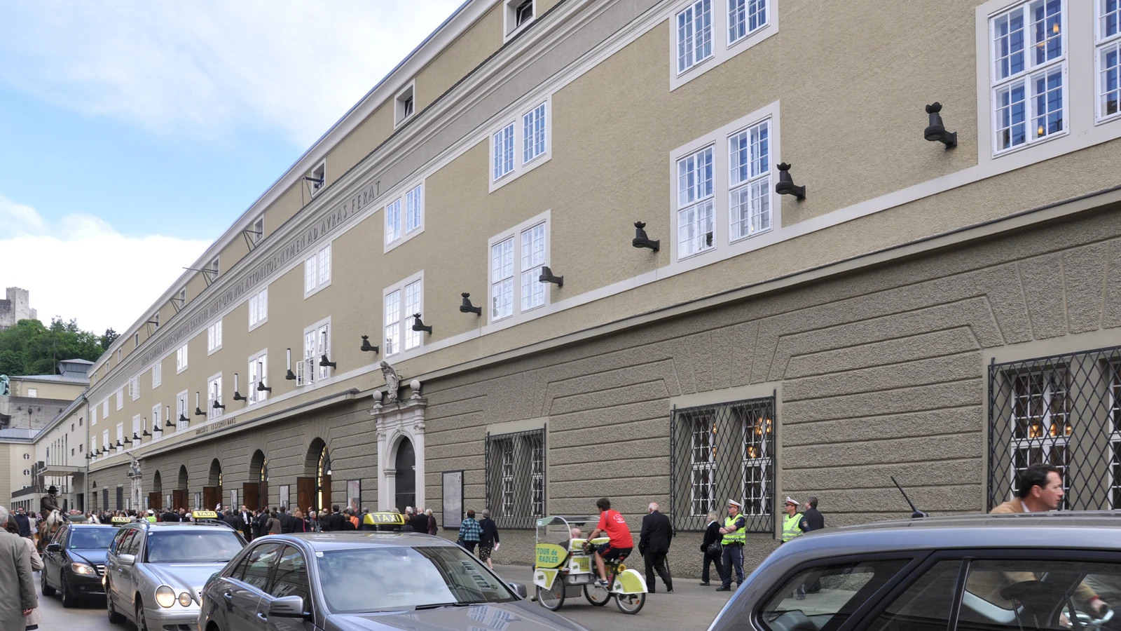 Monumental stone facade of the Großes Festspielhaus along Hofstallgasse in Salzburg.