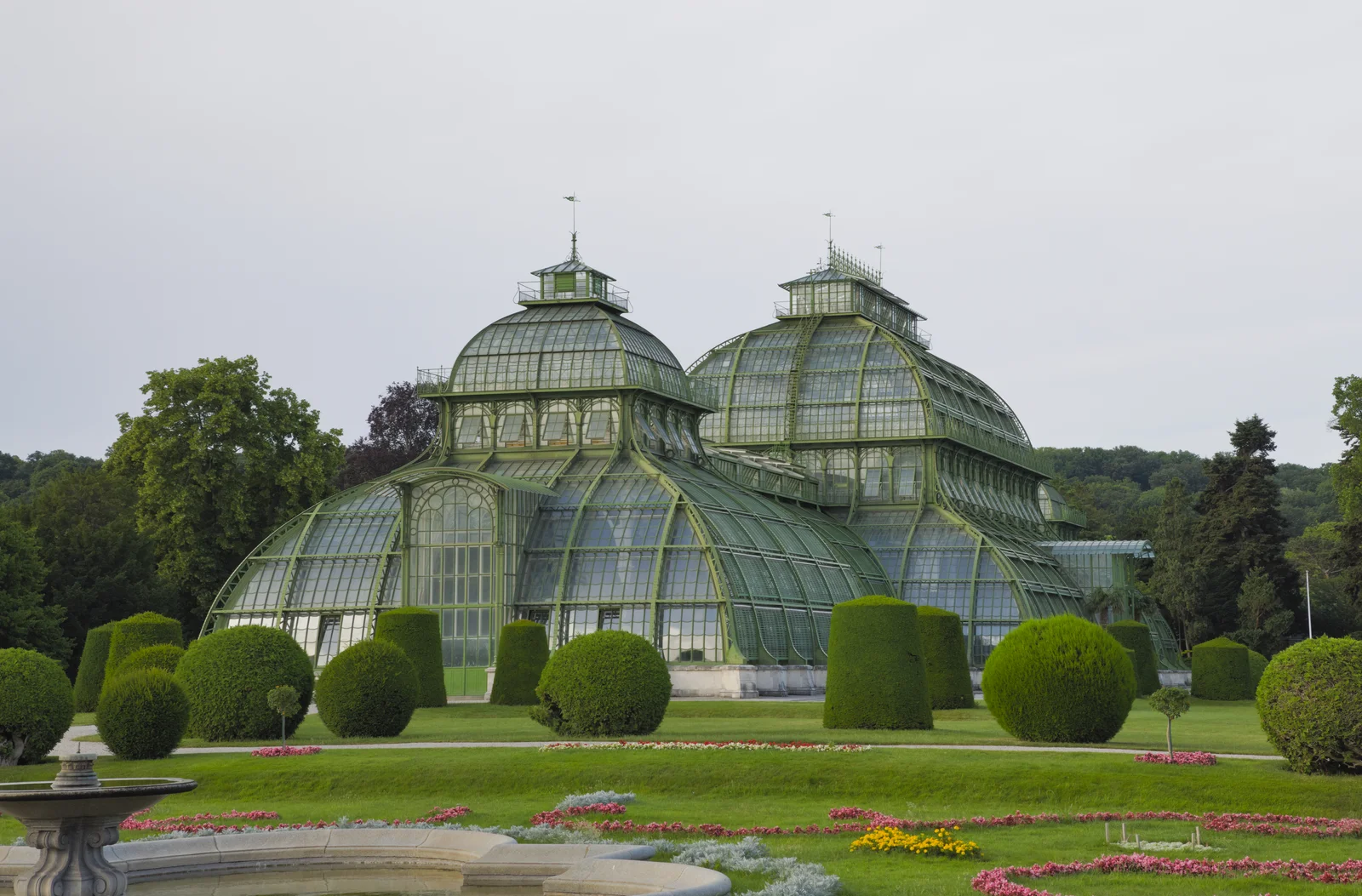 Nineteenth-century wrought-iron and glass conservatory set among manicured gardens and trees.