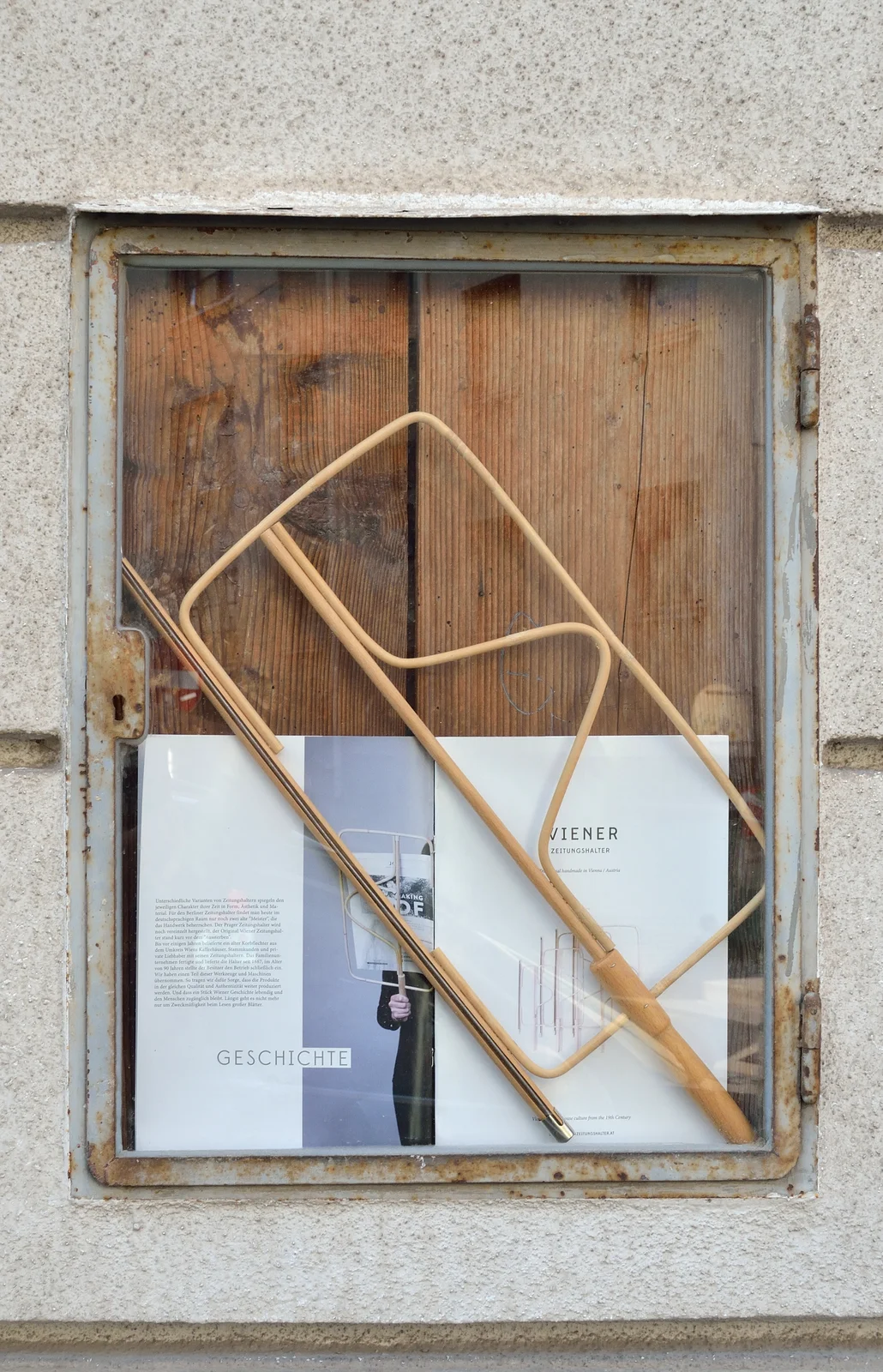 Traditional Viennese curved wooden cane newspaper holder clasping a printed daily Austrian broadsheet.