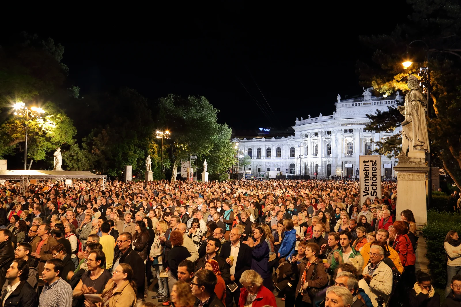 Paved square of Vienna Rathausplatz filled with festival crowds looking towards the Burgtheater.