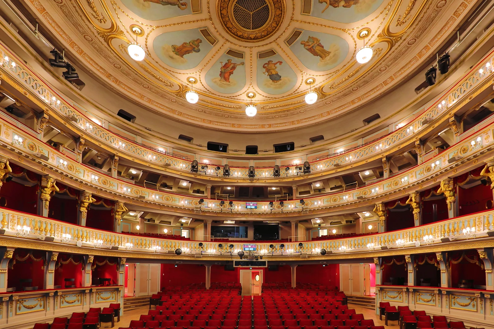 Sumptuous multi-tiered historic theatre auditorium with gilded balconies and red velvet seating in Vienna.
