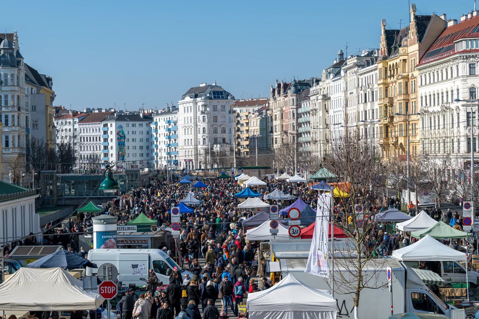Crowds browsing vintage items and antiques at an outdoor flea market in Vienna.