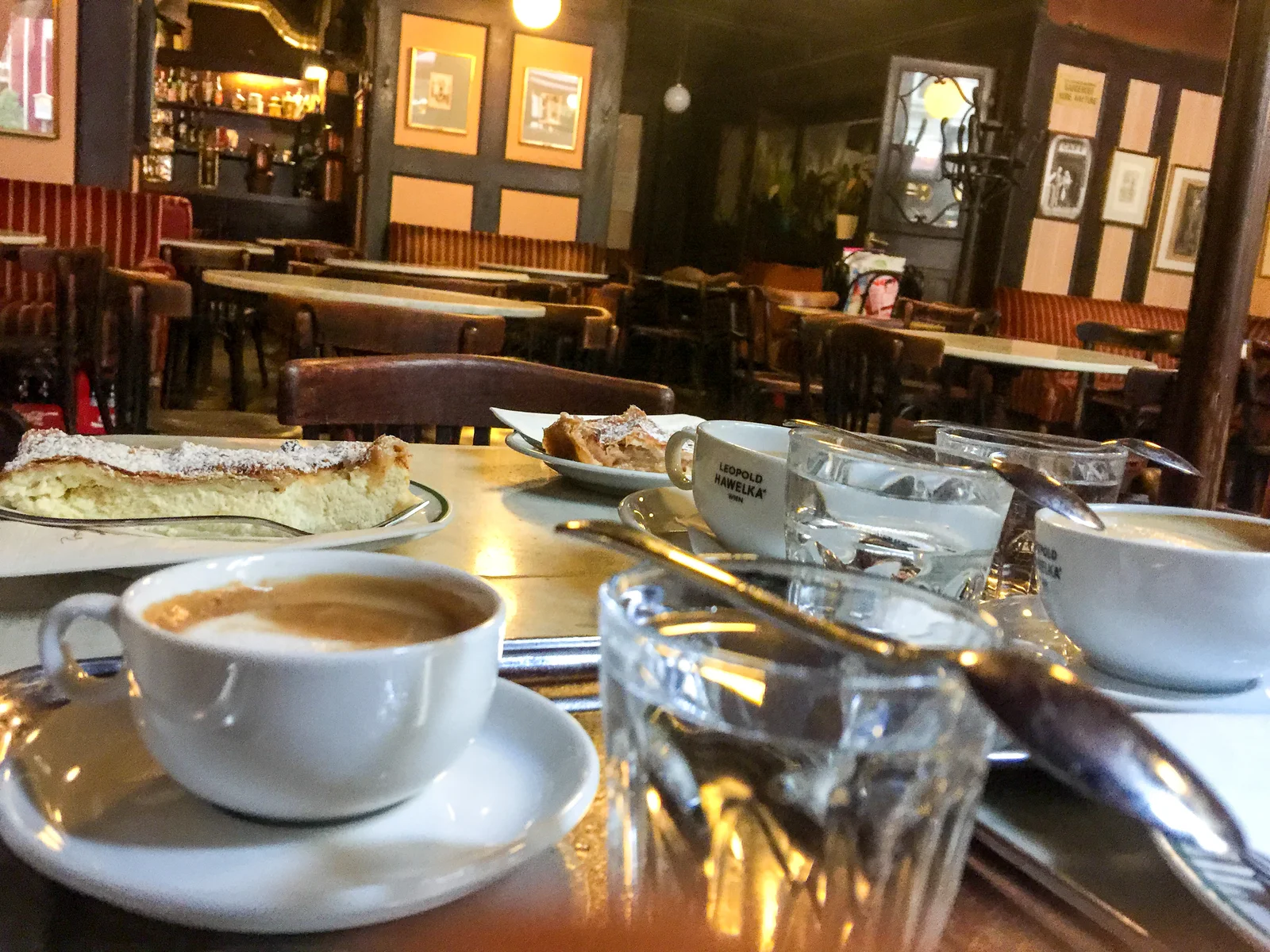 Cozy traditional Viennese coffeehouse interior with posters and dark wood furnishings.