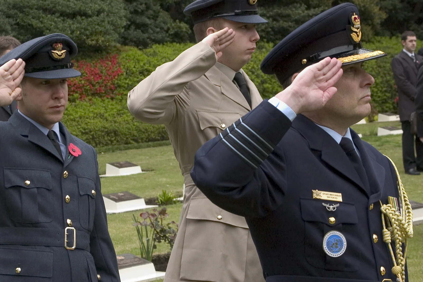 Bugler playing the Last Post bugle call beside a floral memorial wreath.