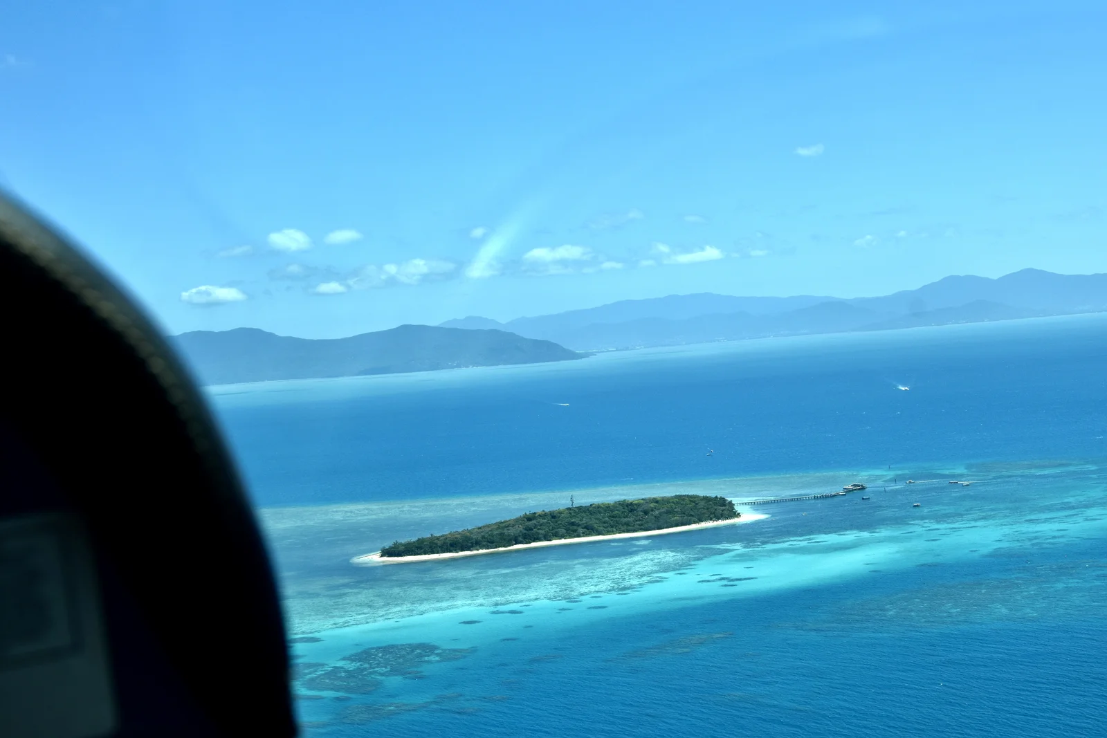 Aerial perspective of shallow coral reef platforms and turquoise marine waters in Queensland.