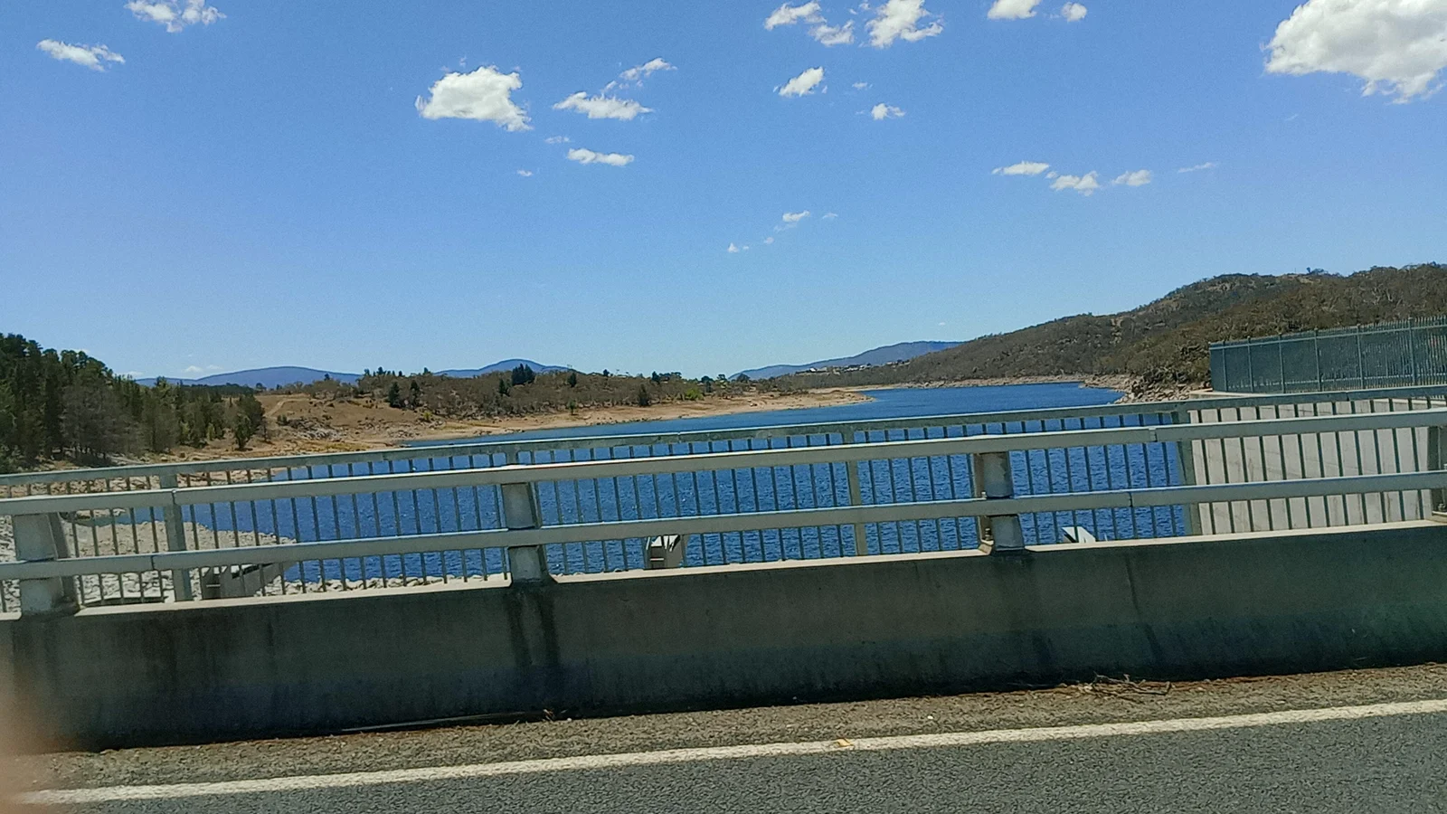 Heavy civil engineering dam structure and road bridge crossing high country alpine water.