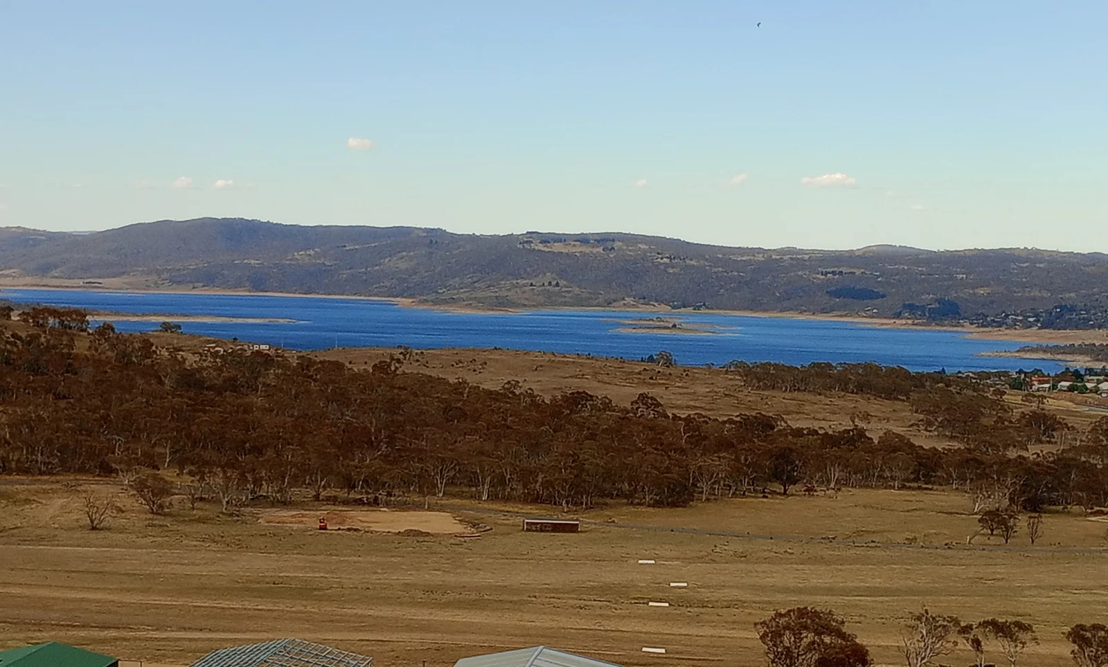 Vast mountain lake surrounded by rugged alpine slopes and rural Australian high country.