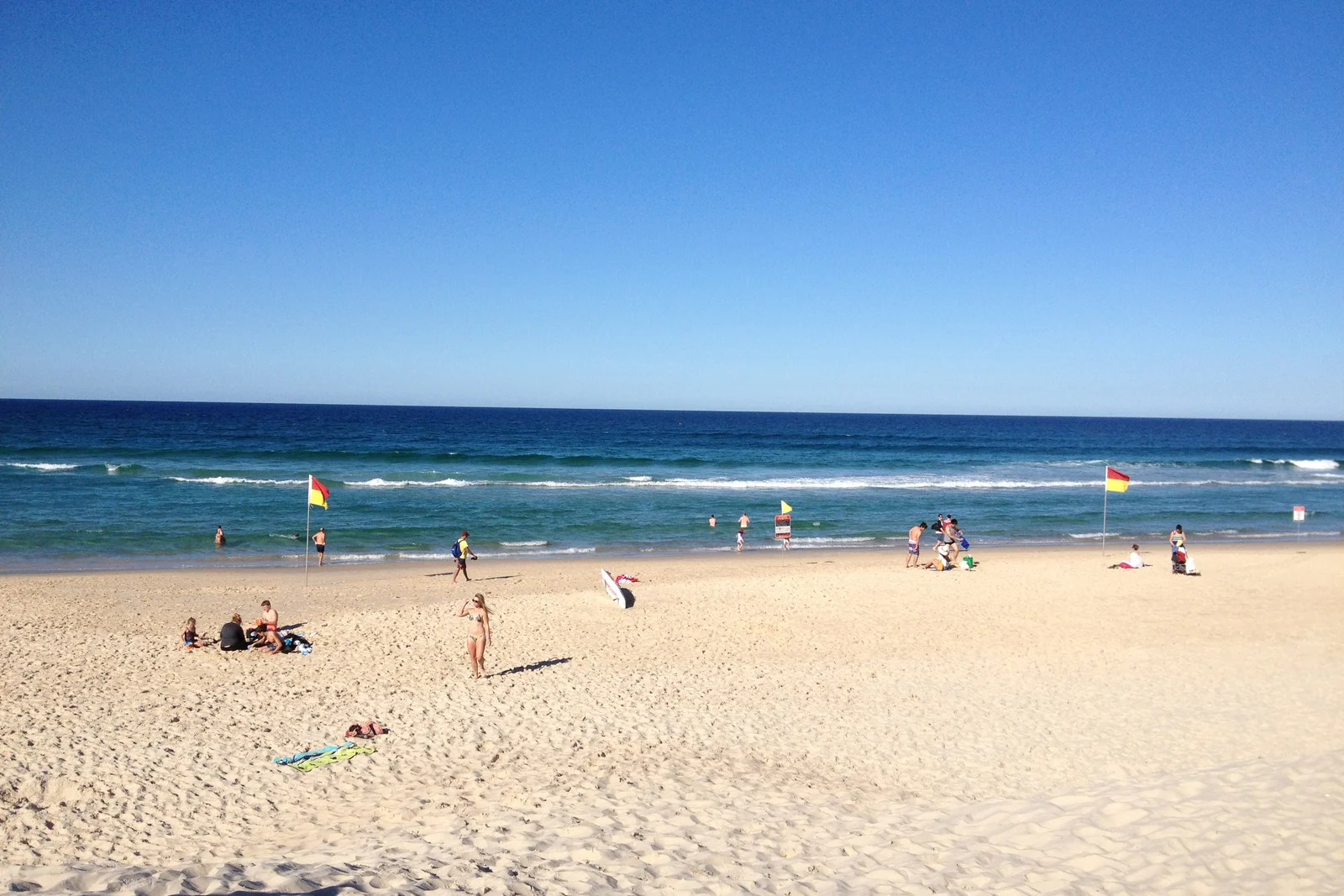 Red and yellow surf lifesaving flags standing in the sand marking the safe swimming area.