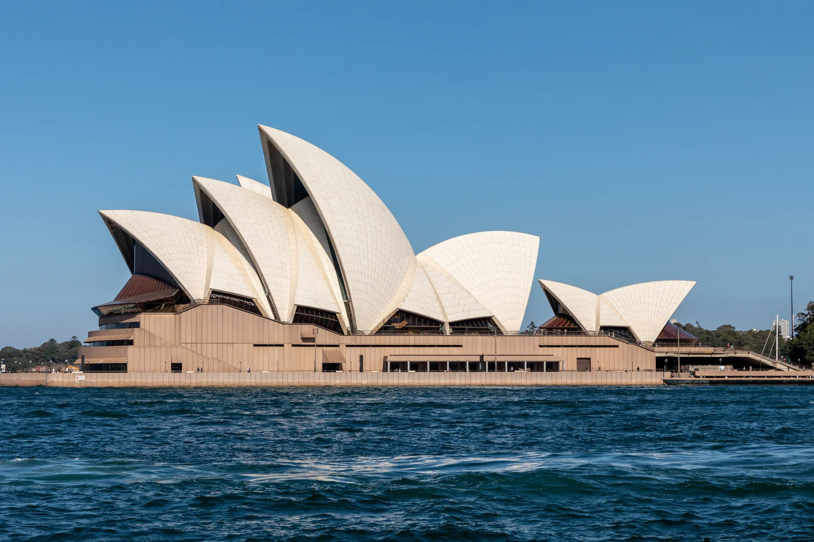 Panoramic view of the Sydney Opera House on Bennelong Point surrounded by Sydney Harbour waters.