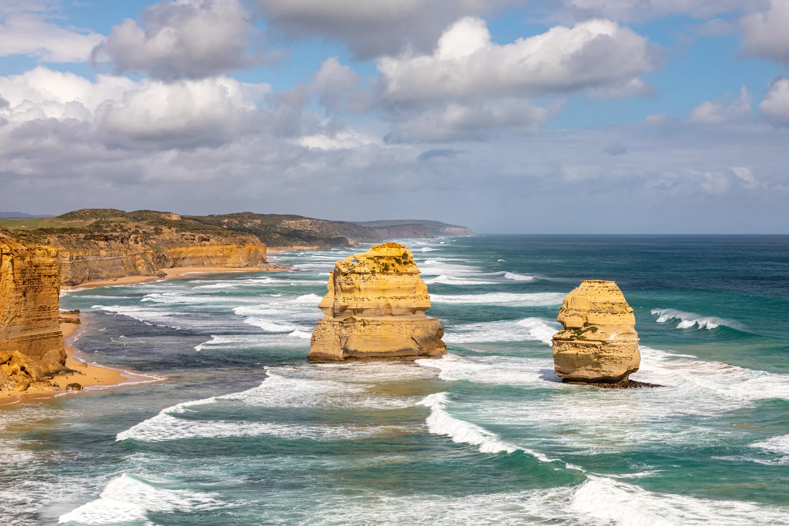 Panoramic view of the Twelve Apostles limestone stacks towering above the ocean surf in Port Campbell National Park.