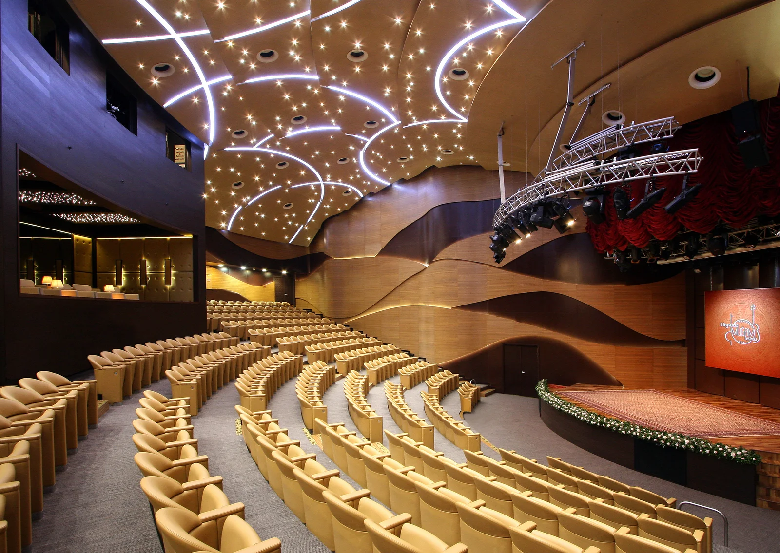 Modern glass and steel architecture of the International Mugham Center illuminated along the Baku Boulevard.