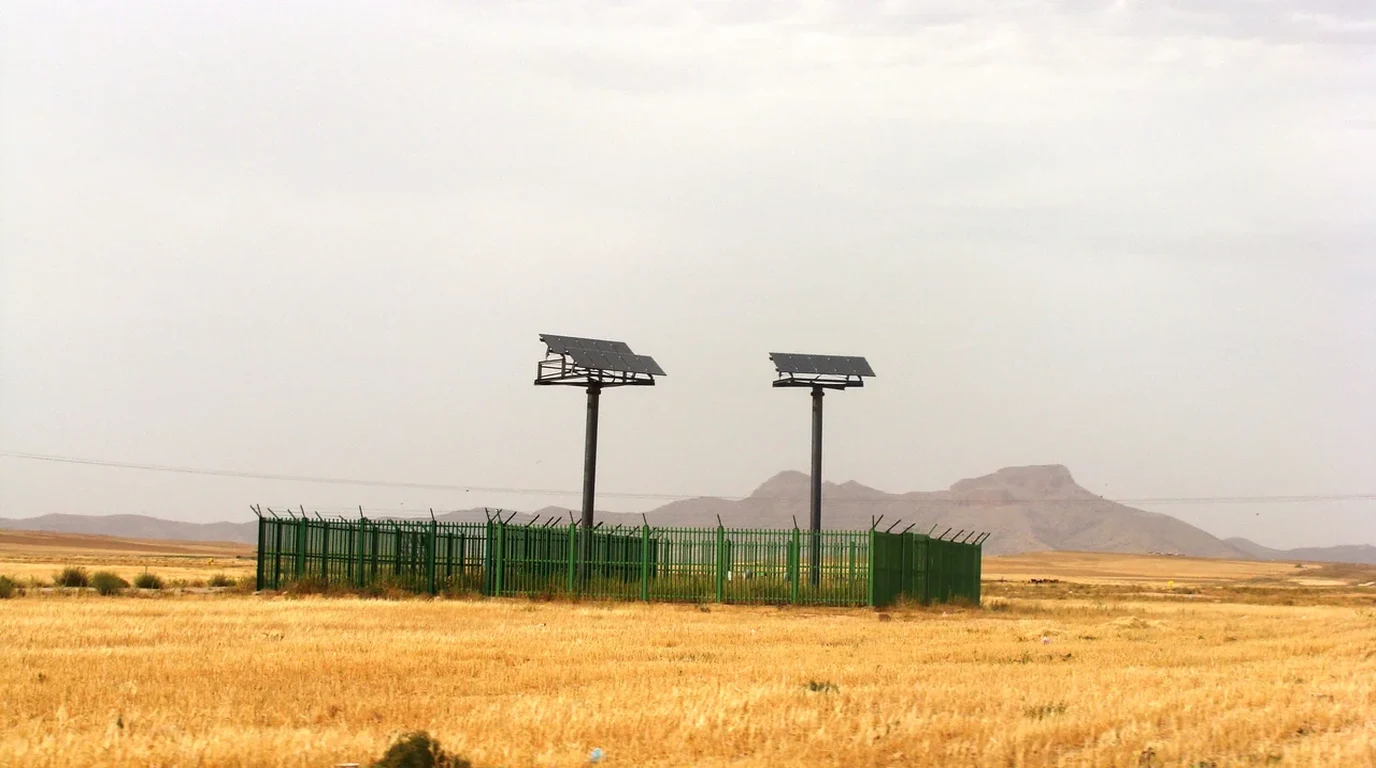 Vast rows of blue solar photovoltaic panels and grid-connected inverter substations across arid landscape.