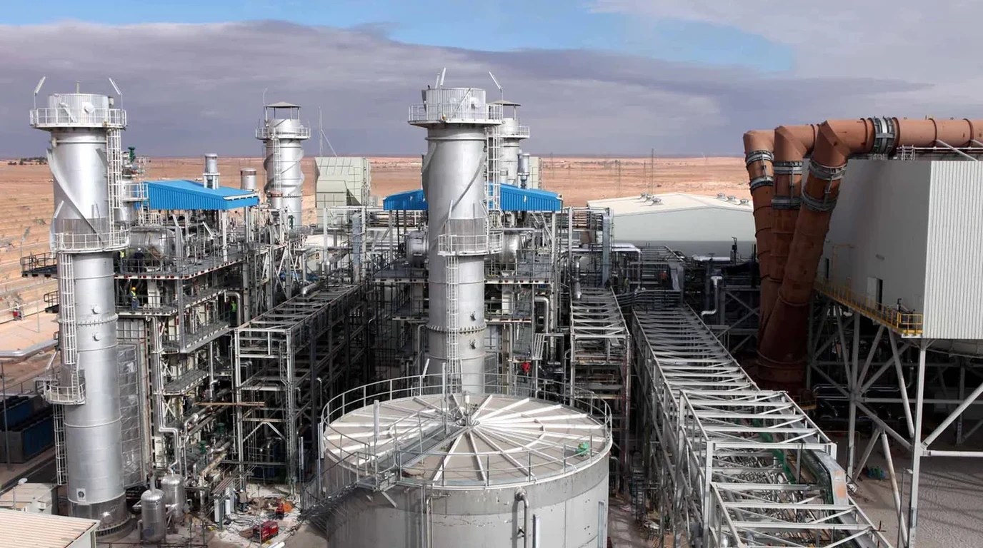 Heavy industrial gas turbine exhaust stacks, steam recovery units, and generator halls at an electric power station.