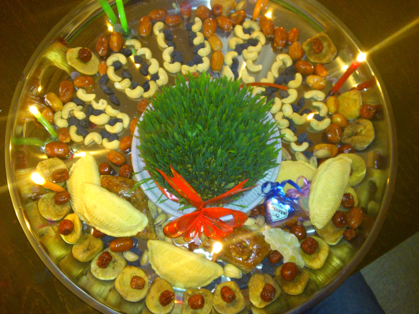 Ceremonial round holiday tray laden with sprouted wheat, colorful dyed eggs, candles, and traditional Azerbaijani pastries.