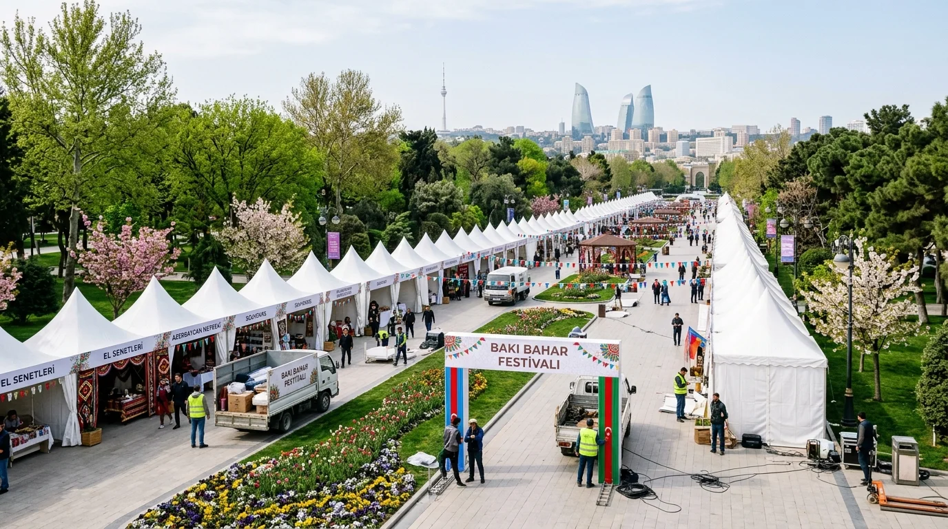 Wide view of Genclik Park in Baku with rows of white festival tents and spring flowerbeds prepared for Novruz celebrations.