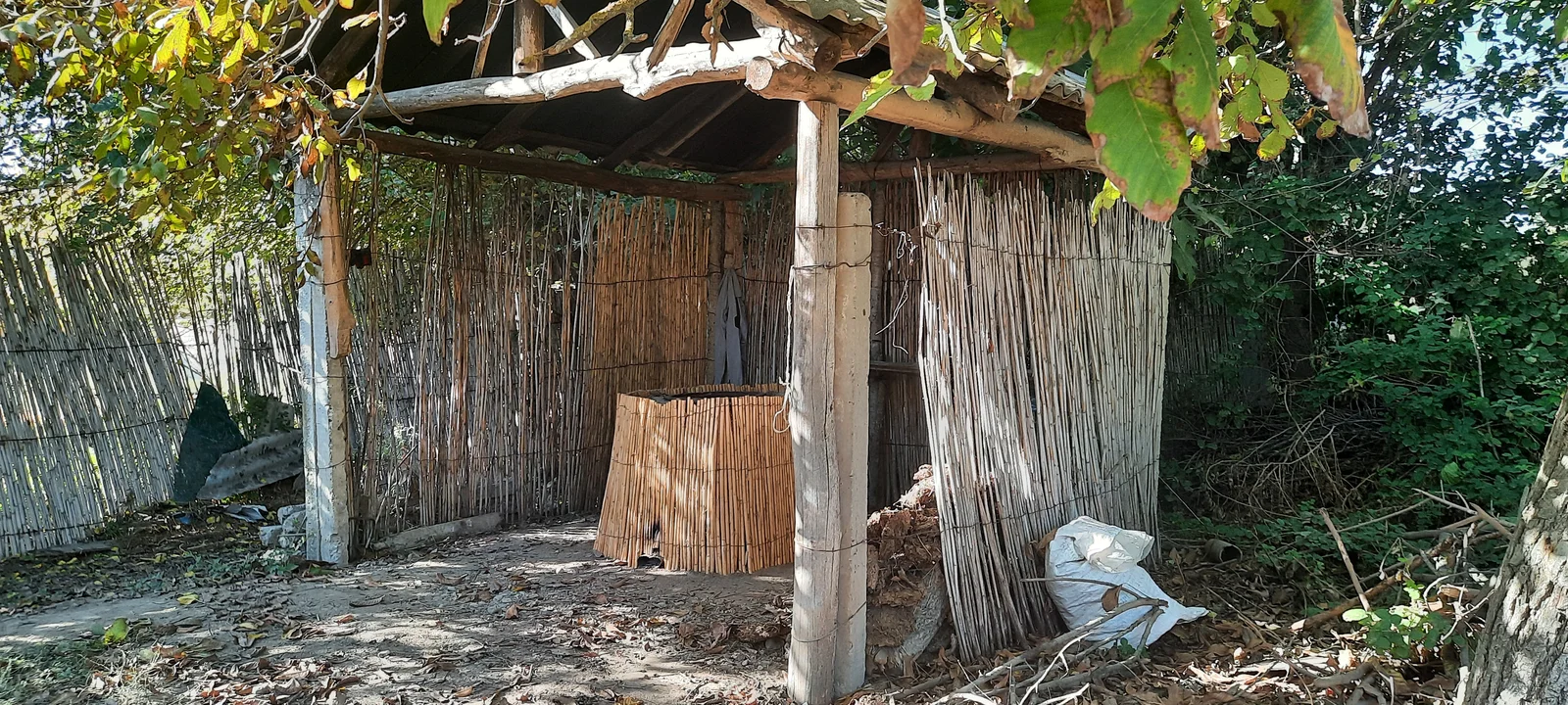 Large cylindrical clay tandir oven built outdoors on stone foundations in a rural Azerbaijani village.