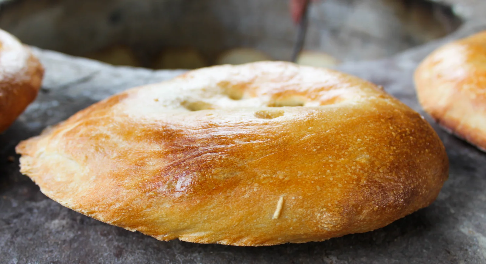 Golden-brown crusty Azerbaijani tandir flatbread loaves arranged fresh from the oven on wooden boards.