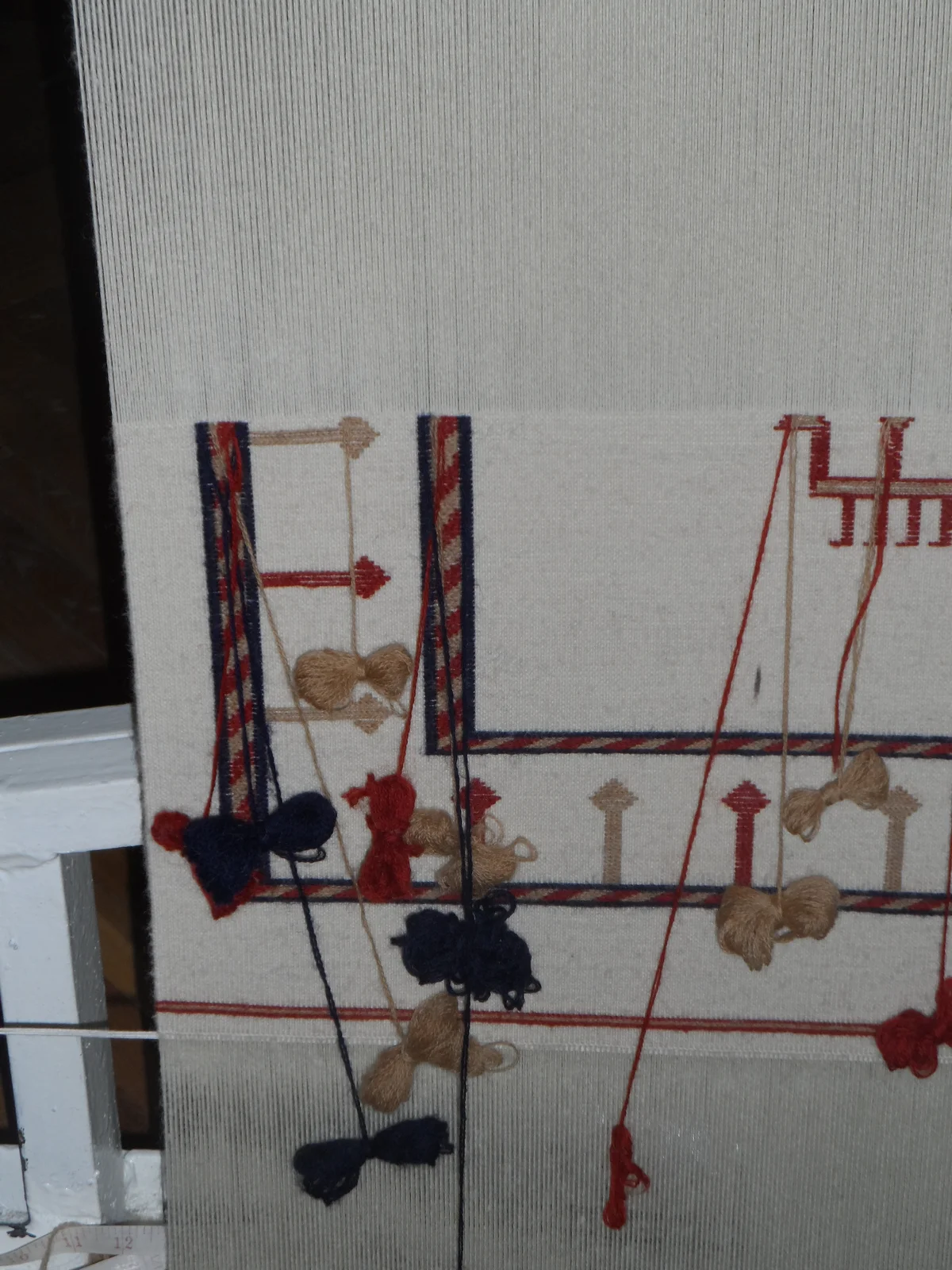 Weaver interlacing colorful wool weft threads into a flat-weave kilim on an upright wooden frame.
