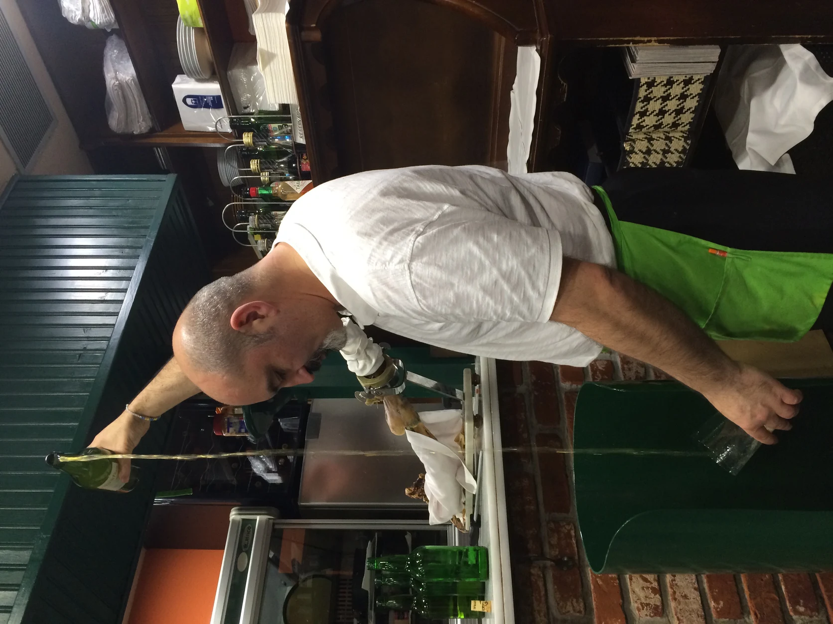 Waiter pouring natural Asturian cider from an overhead height in a traditional sidrería.