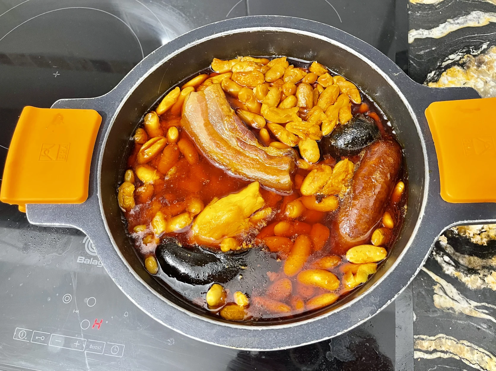 Traditional earthen casserole of fabada asturiana with large white beans and compangu meats.
