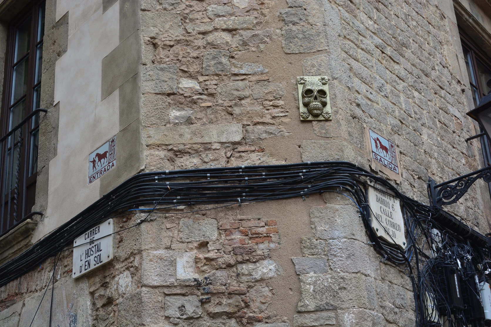 Historic ceramic and enamel street plaque affixed to Gothic Quarter stone masonry.