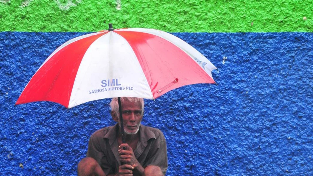 A pedestrian sheltering from a sudden heavy tropical downpour under a shop veranda in Colombo.