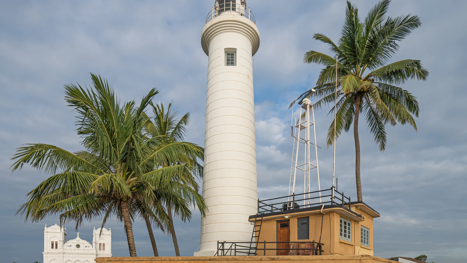 The historic white lighthouse rising above the stone ramparts of Point Utrecht Bastion in Galle Fort.