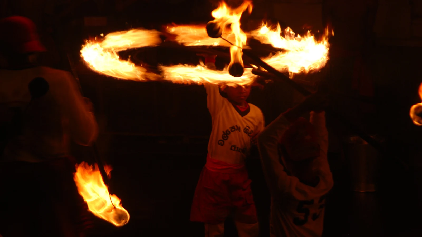 Acrobatic fire dancers spinning blazing coconut-husk torches to clear the nocturnal processional route.