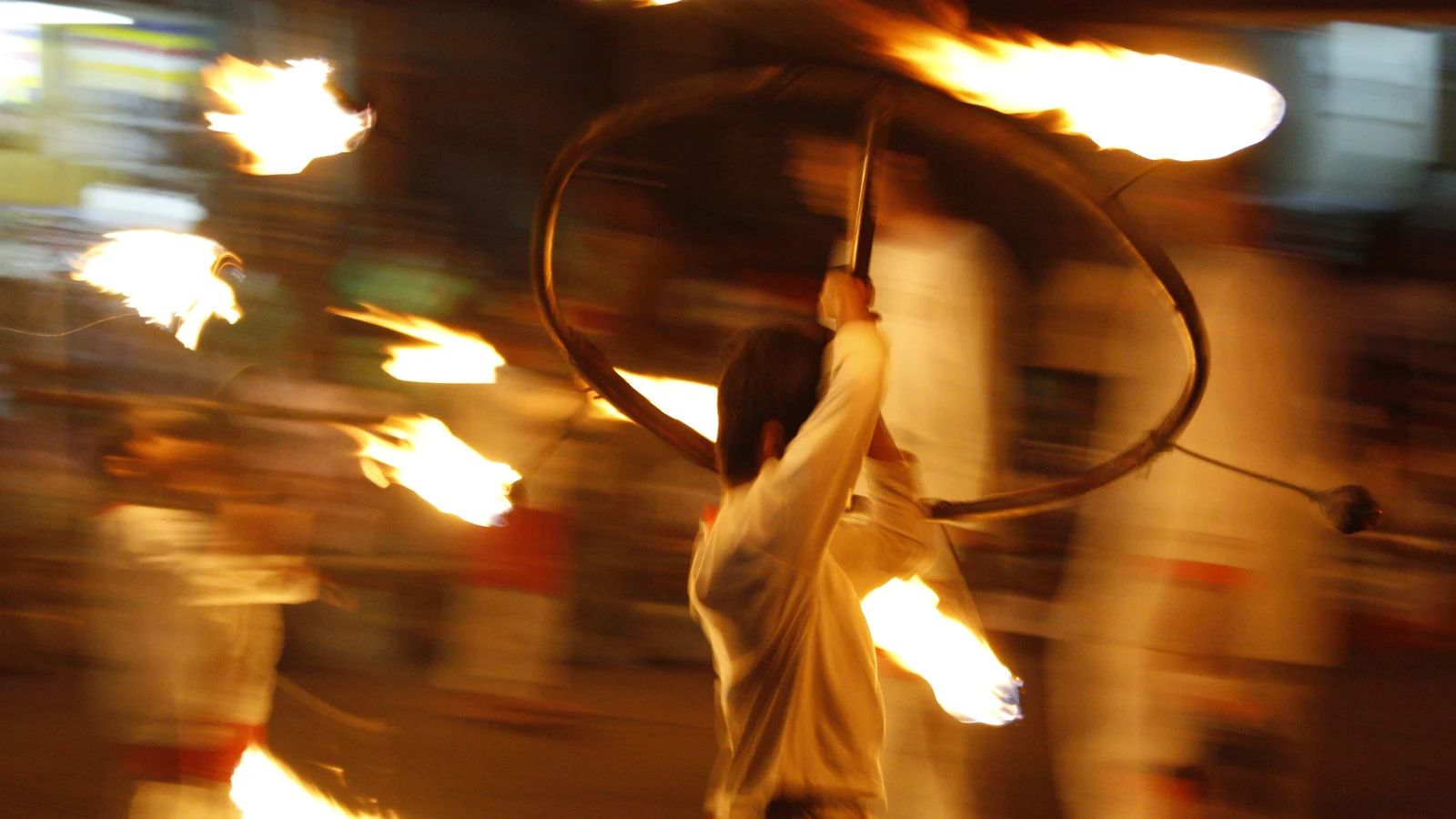 A traditional performer manipulating a giant flaming wheel during the Kandy Esala Perahera.