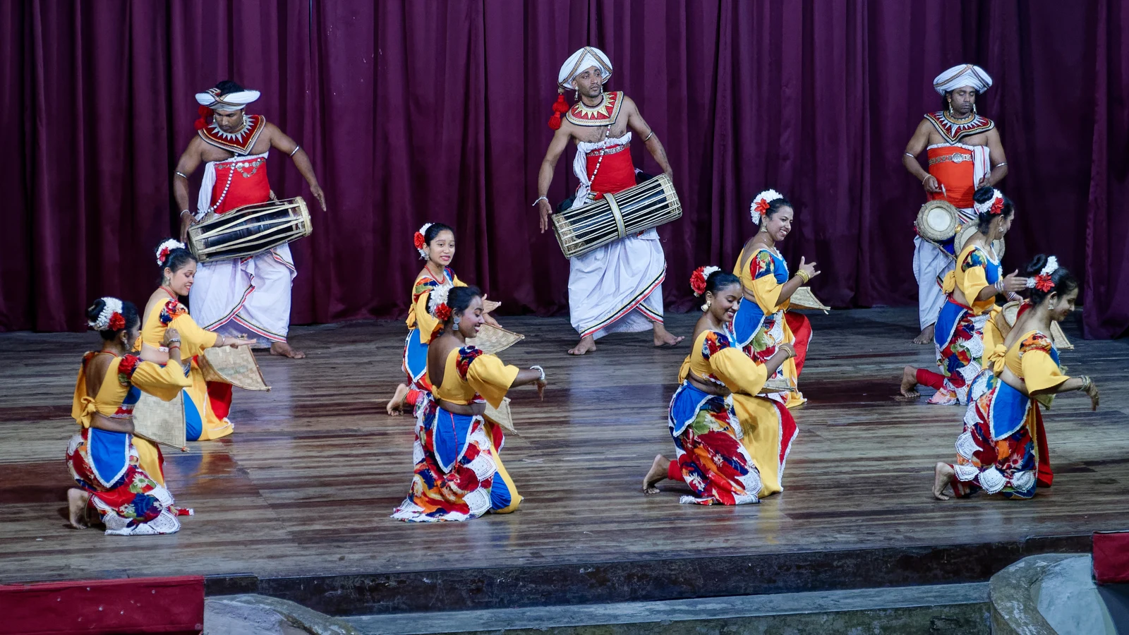 Female performers executing graceful expressive hand gestures during a classical Kandyan dance recital.