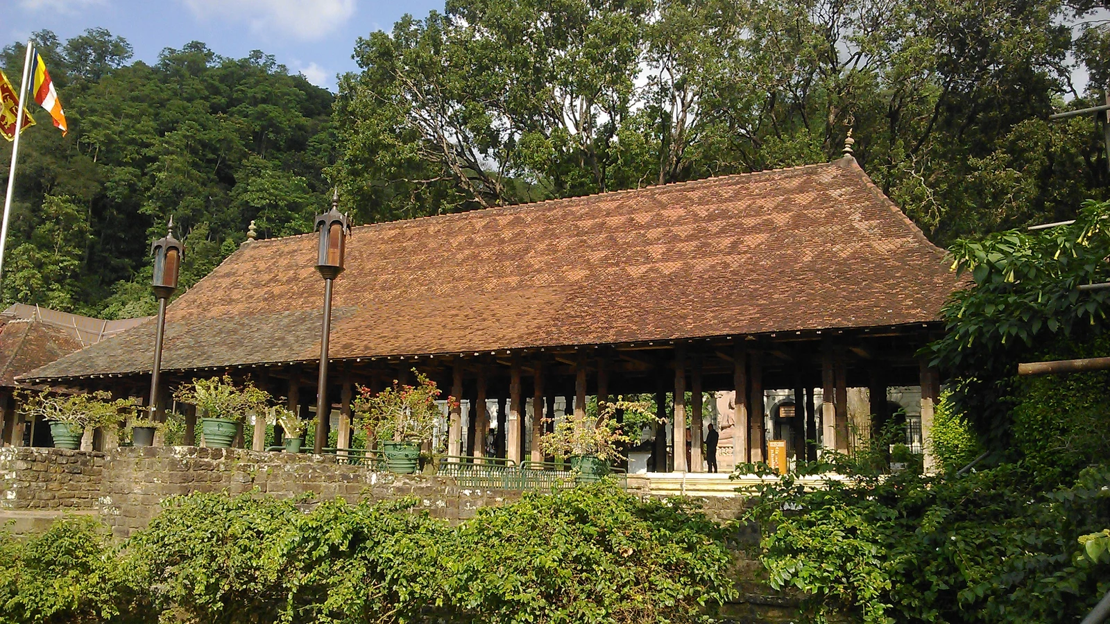 The open-sided Magul Maduwa Audience Hall in Kandy with carved wooden pillars and traditional terracotta tiled roof.