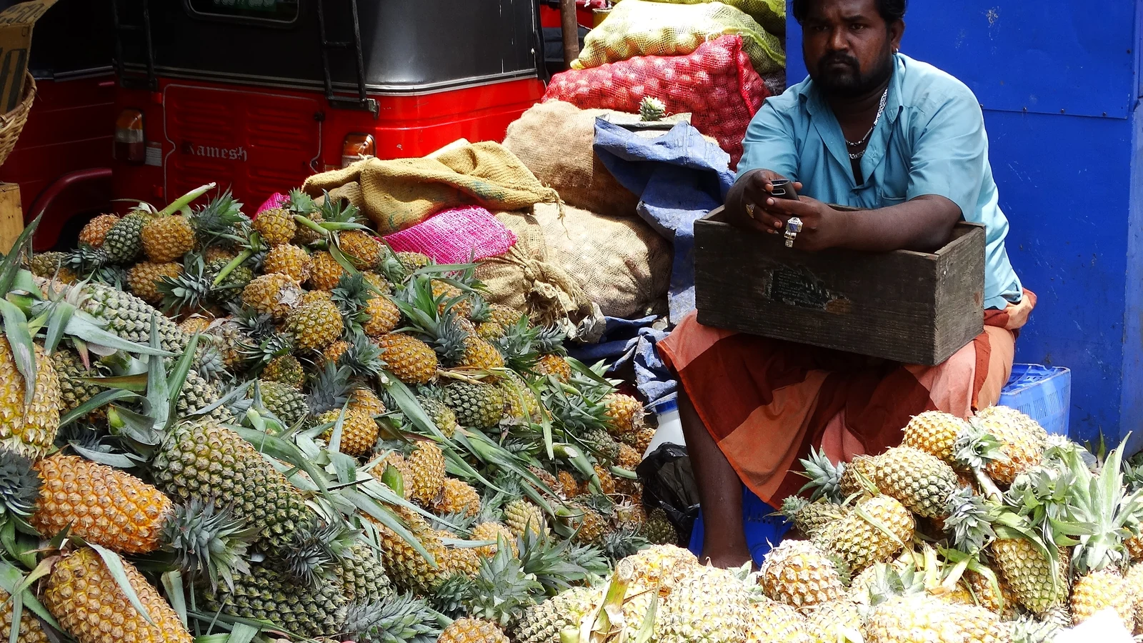Fruit vendor tending crates of fresh tropical pineapples in Pettah market.
