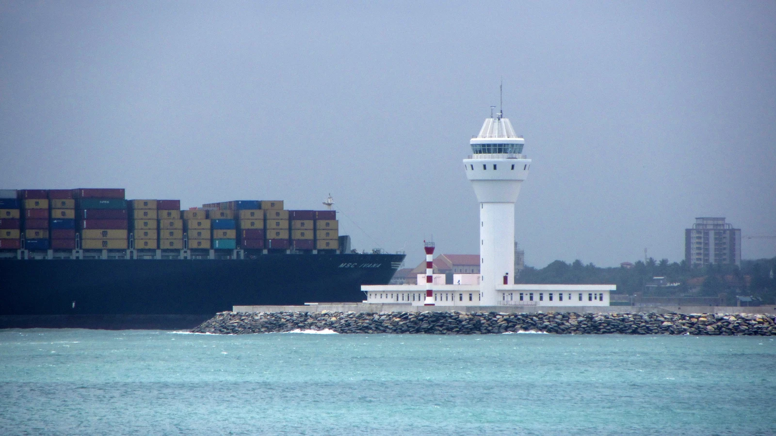 An ultra-large container vessel berthed beneath massive quay cranes in the Port of Colombo.