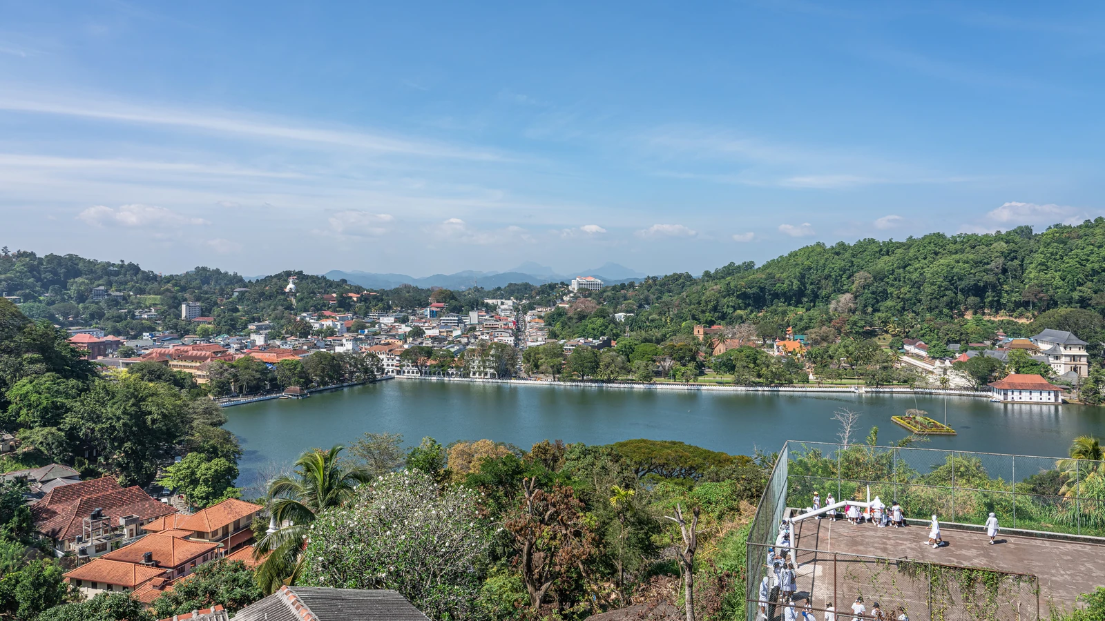 Panoramic view of Kandy Lake and the sacred city nestled among forested mountain ridges.