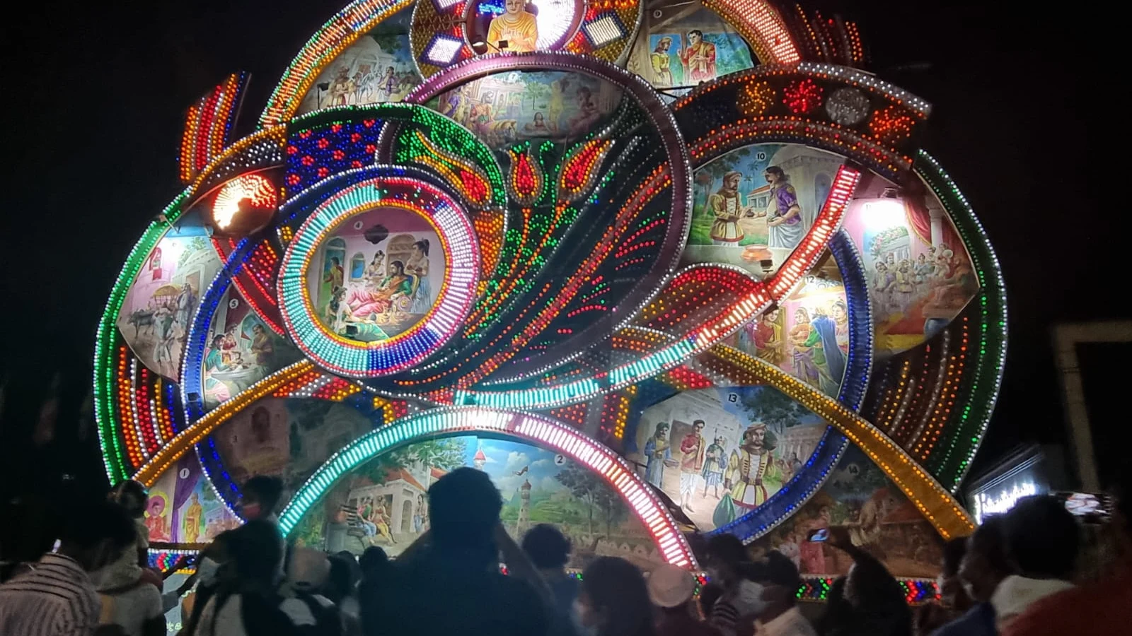 A massive multi-story illuminated Vesak pandol glowing with thousands of colorful lights in Colombo.