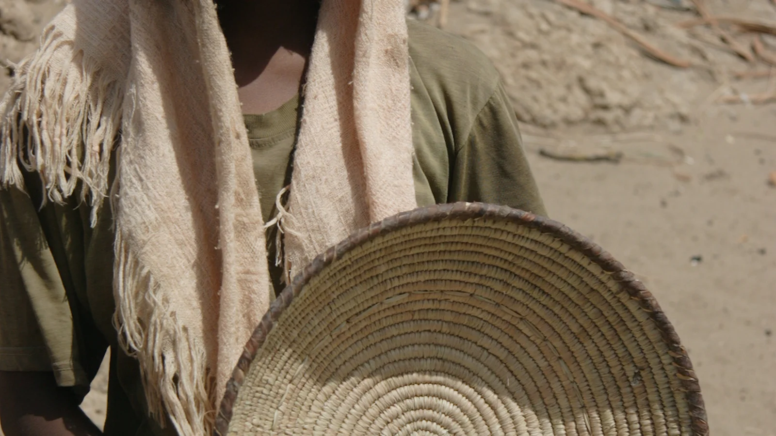An artisan displaying a handcrafted tabaq food cover plaited from wild dom palm leaflets in northern Sudan.