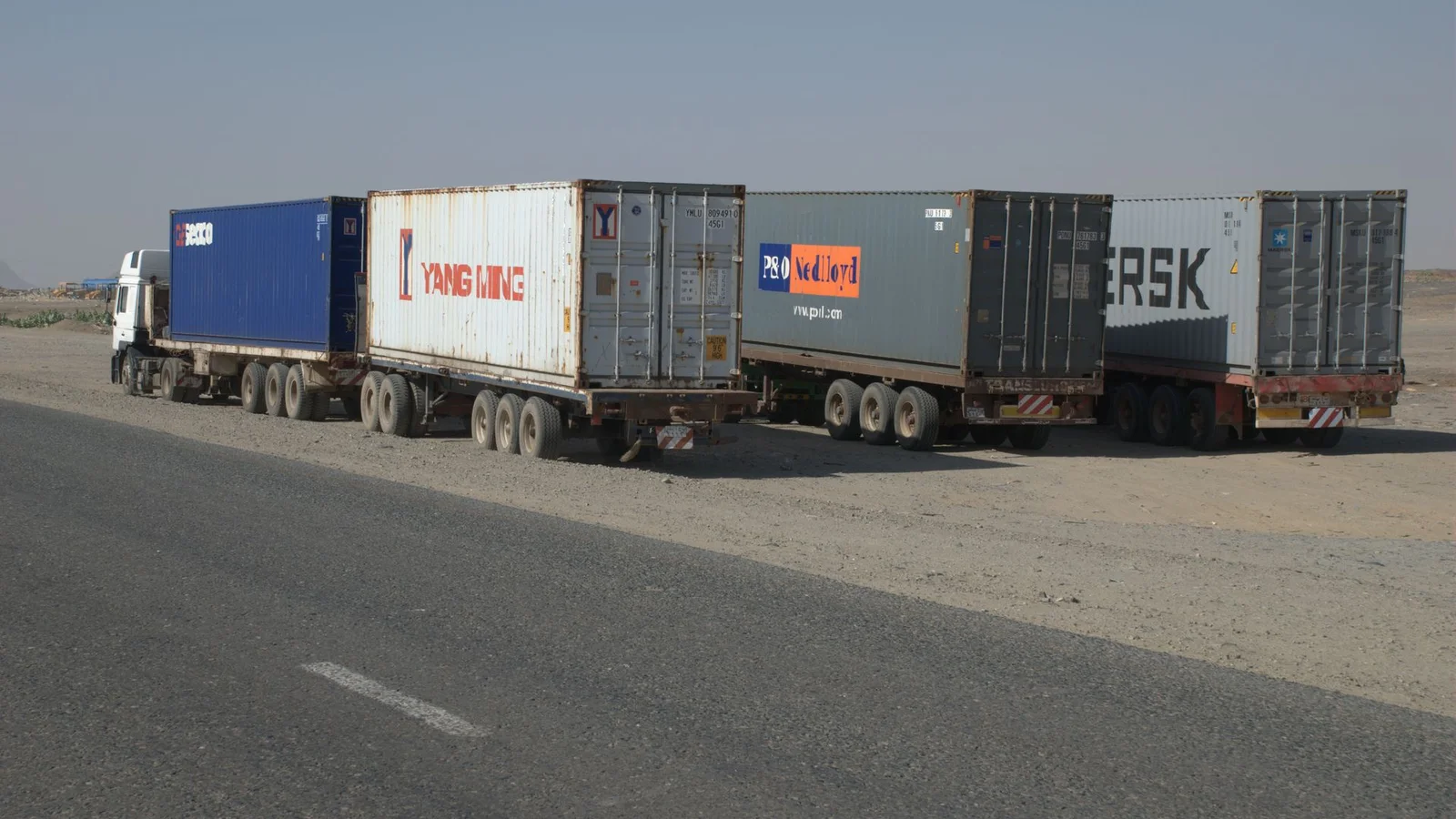 Heavy transport trucks and municipal utility hauliers moving through Port Sudan roadways.