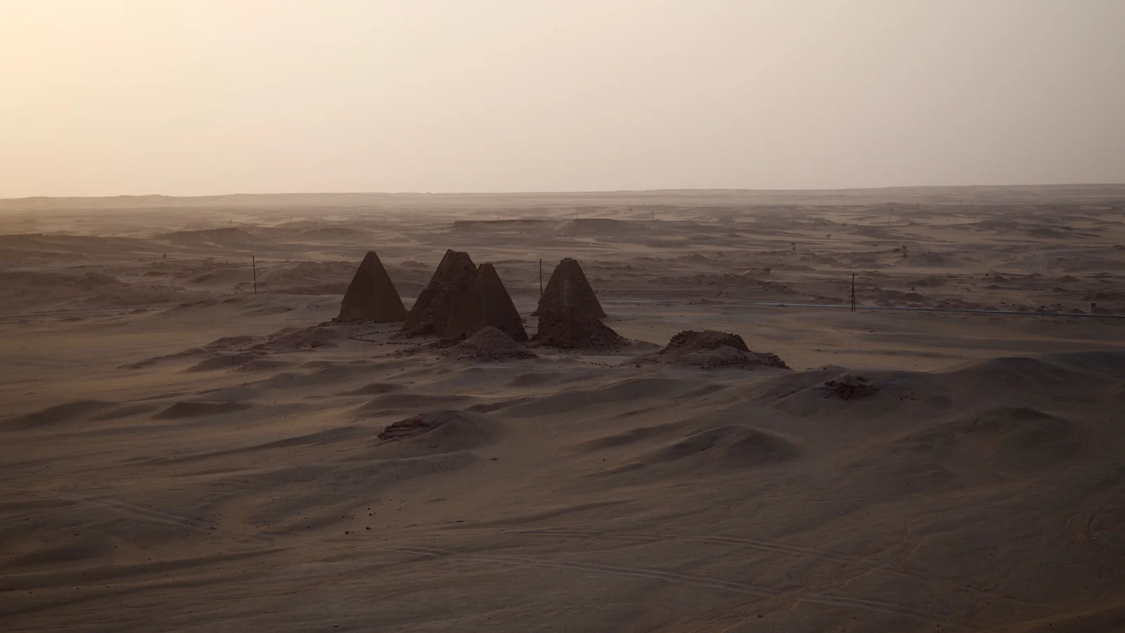 Steep-sided sandstone Kushite royal pyramids rising from desert sands near Jebel Barkal.