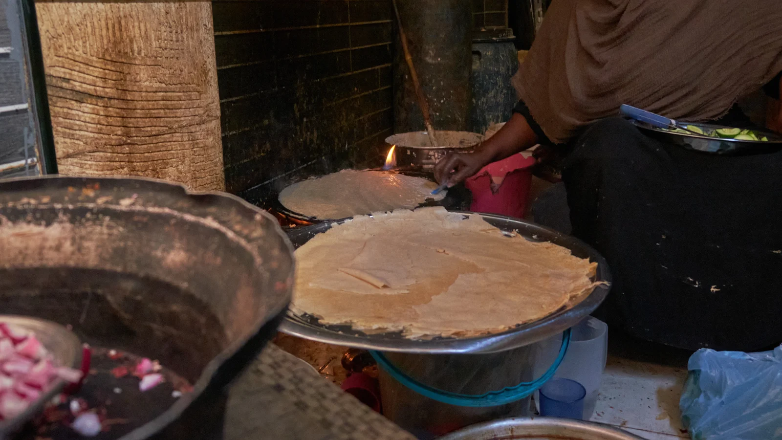 Freshly baked sheets of fermented sorghum kisra flatbread arranged neatly on a woven dining tray.