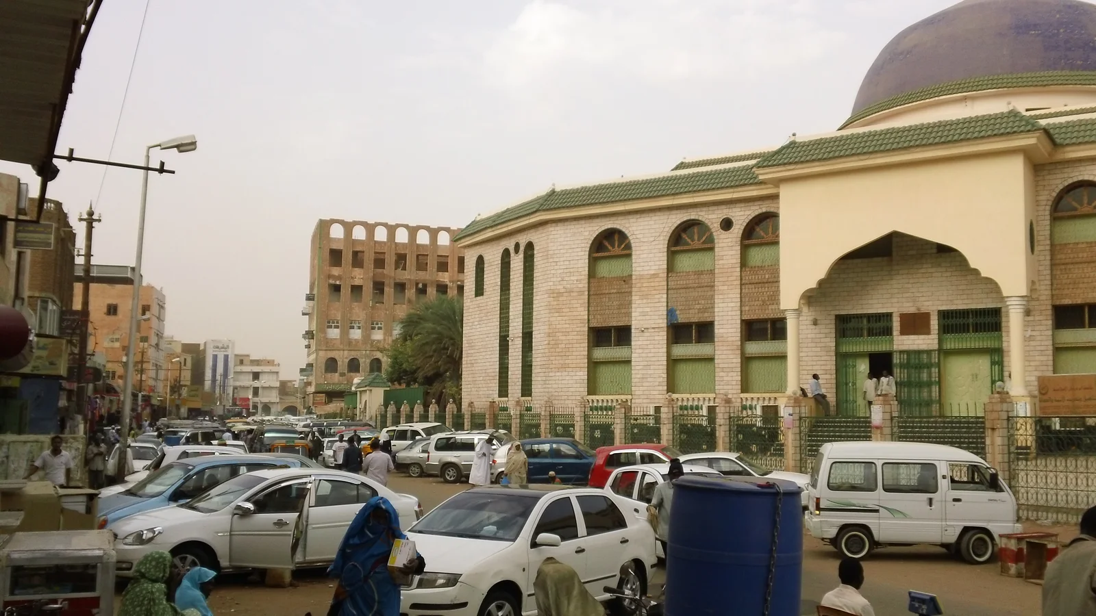Pedestrians and traders walking through the busy main commercial thoroughfare of Souq Omdurman.