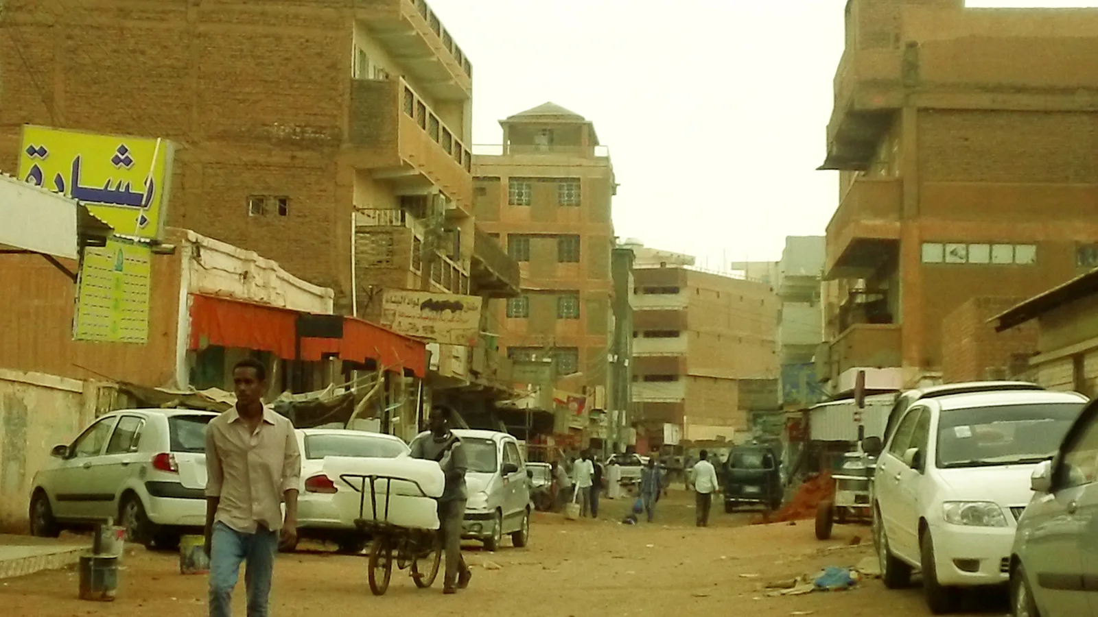 Shaded market alleyways lined with merchant shops and textile awnings in Souq Omdurman.
