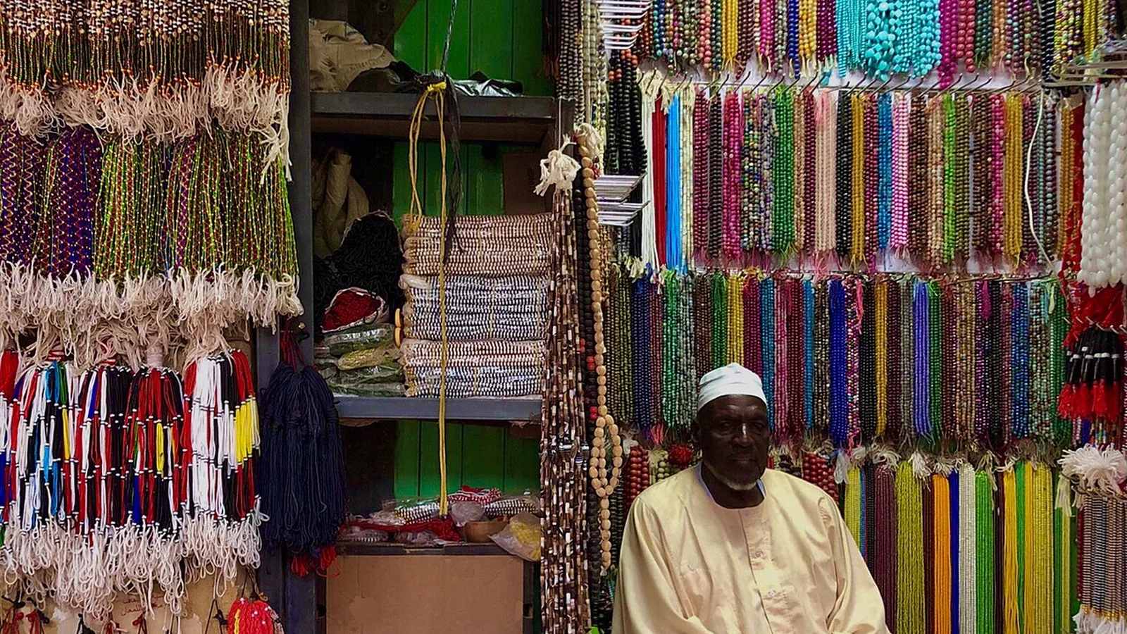 Covered marketplace alley in Souq Omdurman lined with vibrant retail stalls and artisan workshops.