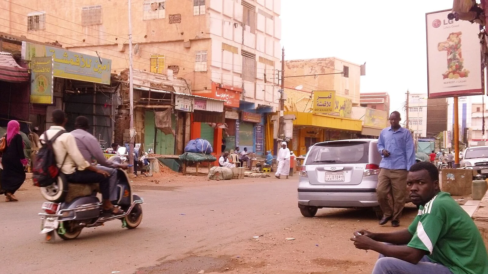Bustling trade lane in Omdurman market with storefronts displaying domestic metalware and handmade goods.