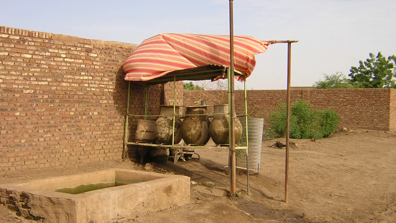 Public standpost tap discharging piped water into household buckets.