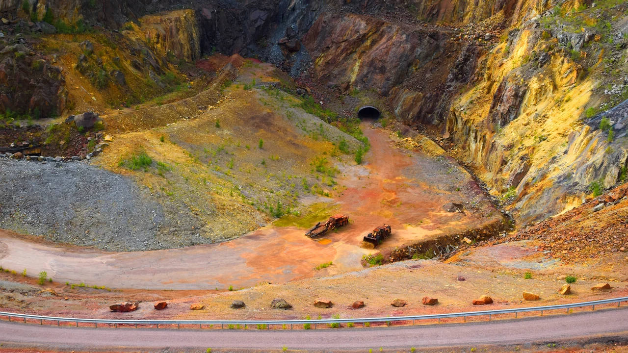 The vast open chasm of Stora Stöten at Falun Copper Mine with steep ochre-colored mineral rock walls.