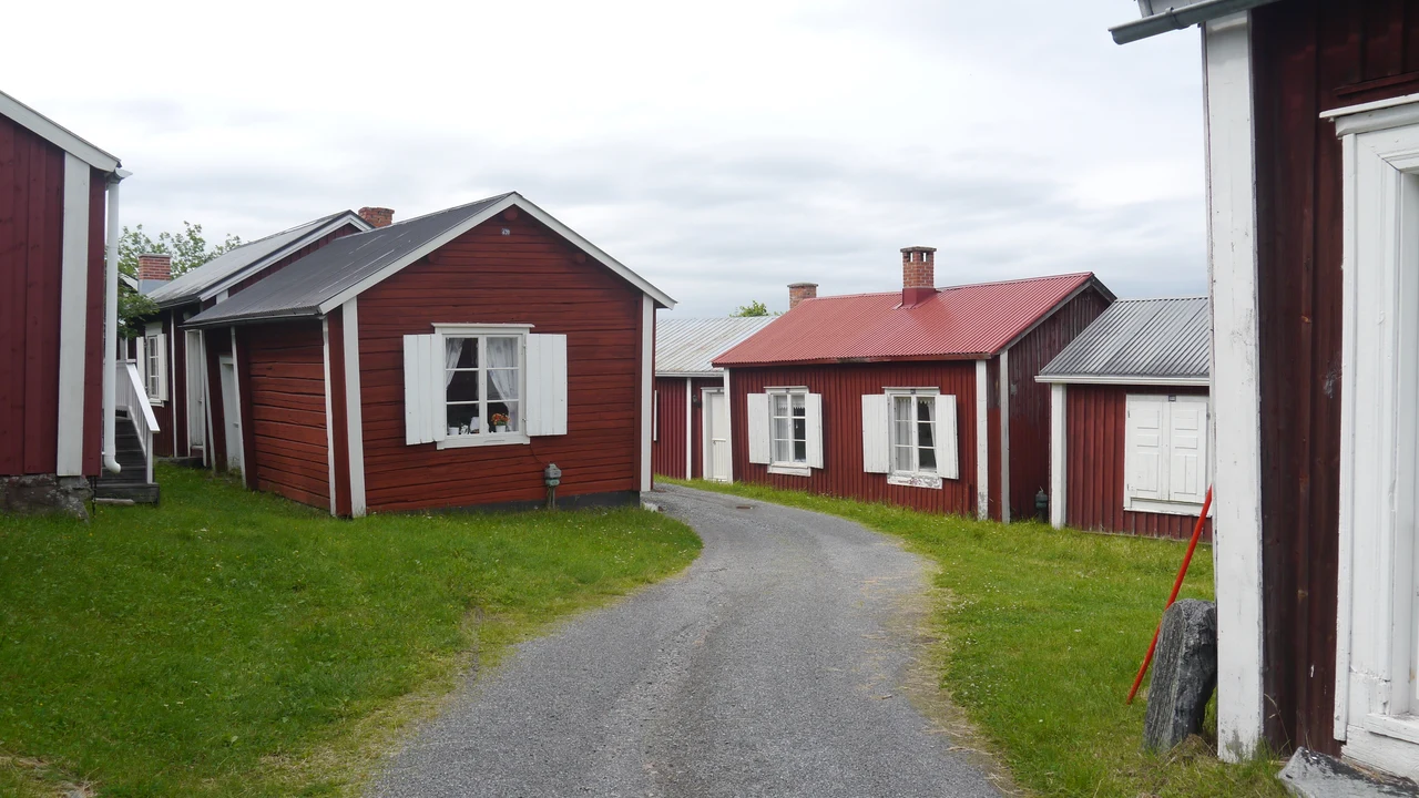 Detailed view of traditional wooden church cottages with white window frames and shingle roofs in Gammelstad.
